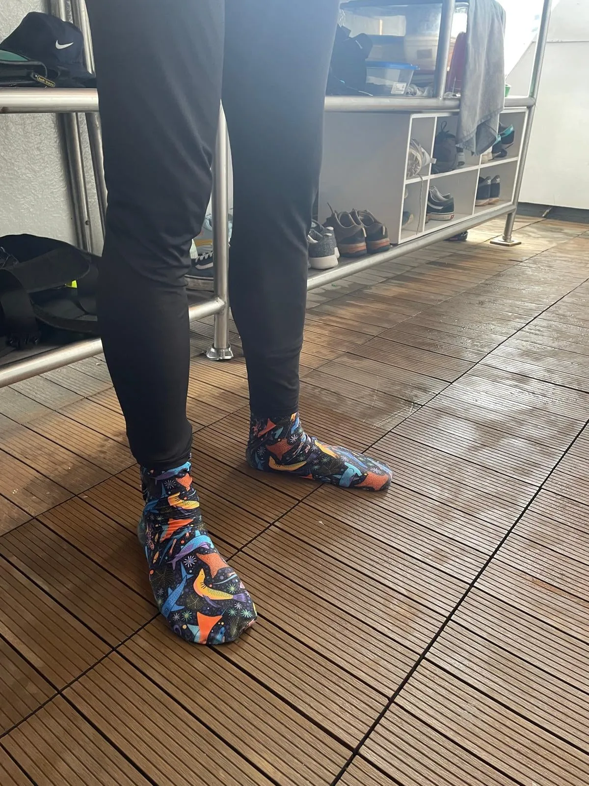 Dive socks worn on the feet with the wetsuit leg pulled down over them, on a wet boat deck