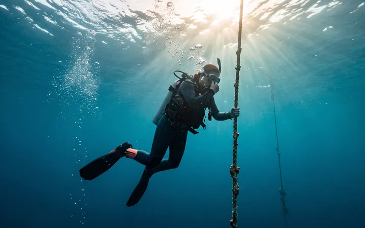 Diver equalizing ear pressure while descending along a mooring line