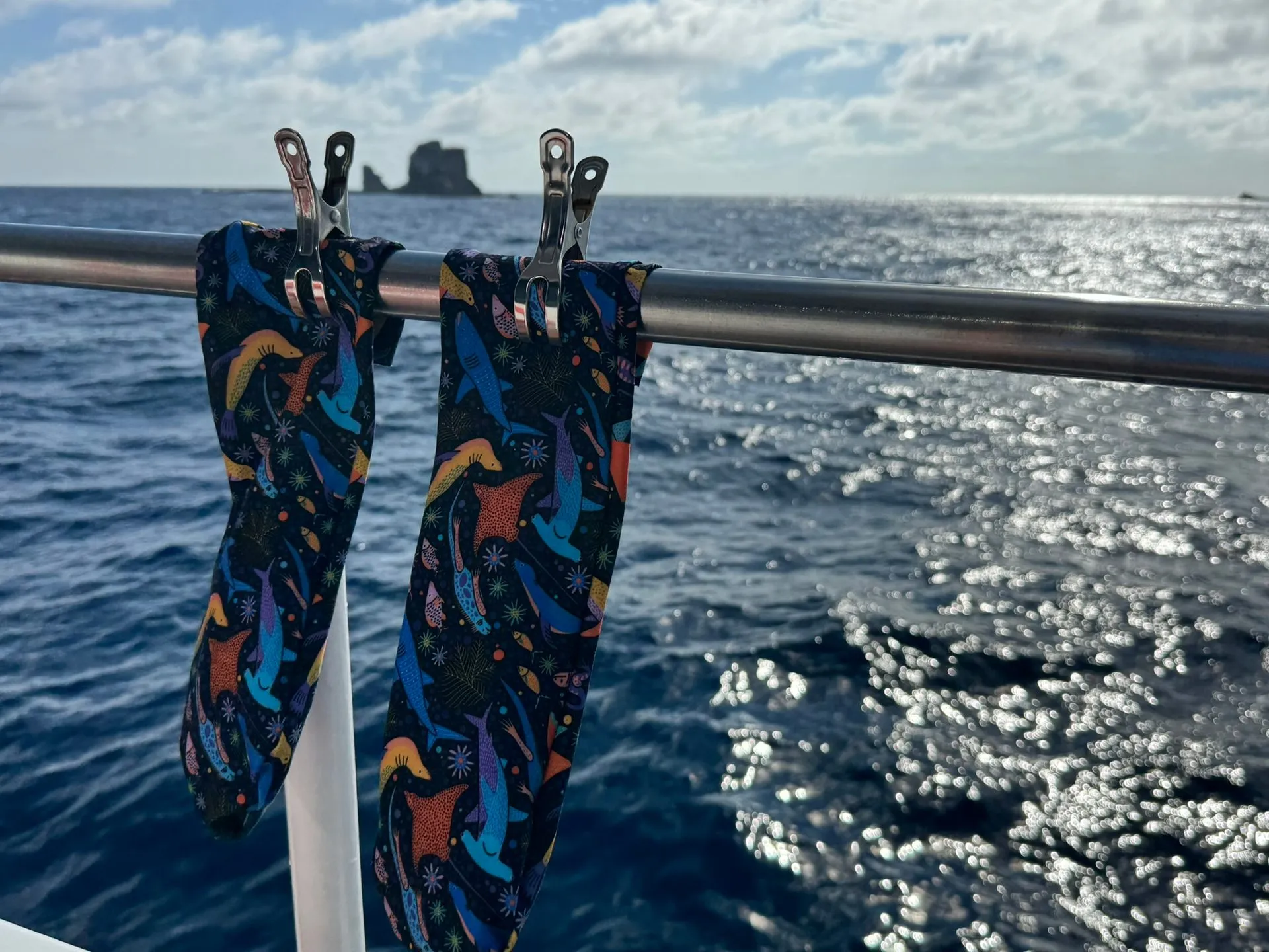 Two hand-sewn prototype socks drying on a boat railing