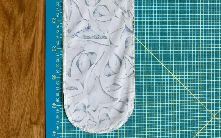 An early dive sock prototype lying inside out on a cutting mat next to a ruler