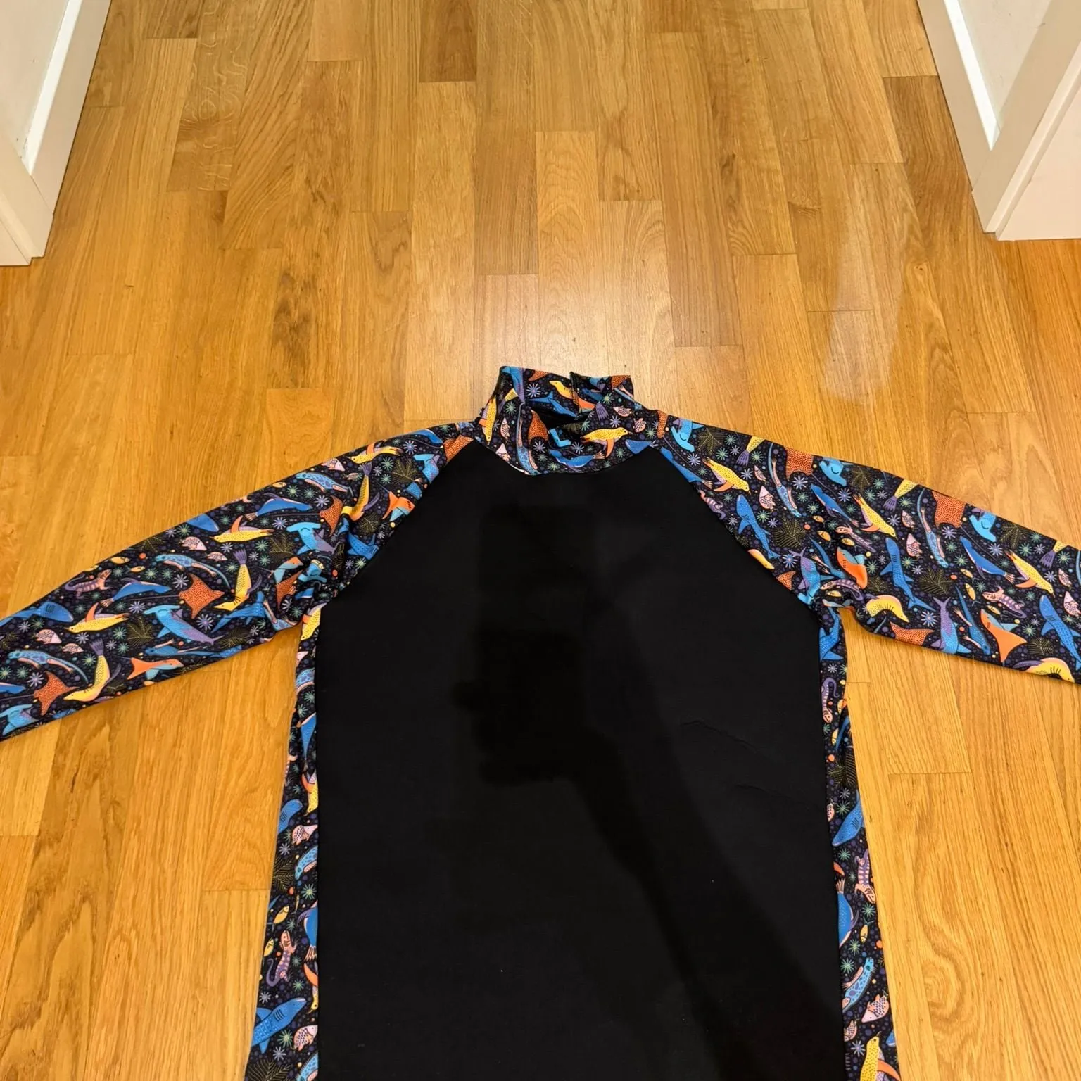 A hand-sewn rashguard prototype in black with printed raglan sleeves