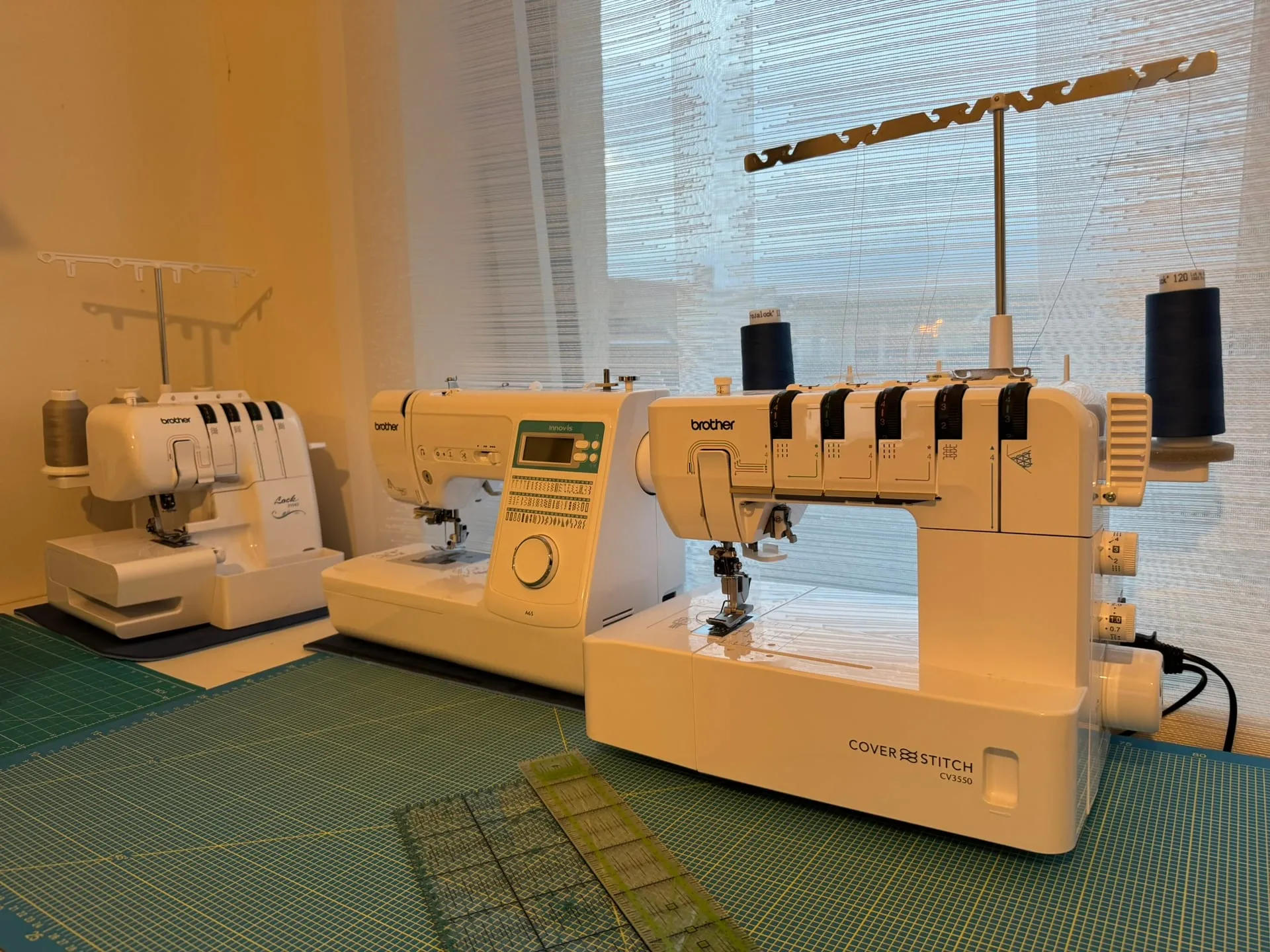 Three sewing machines side by side: an overlock, a sewing machine and a coverstitch machine