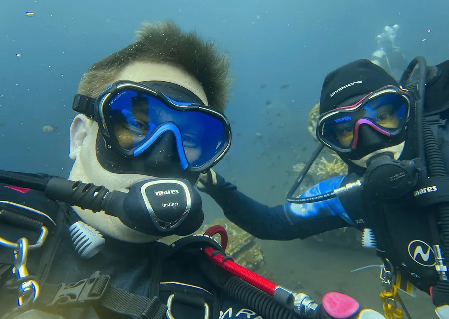 Caroline and Jonas underwater in full dive gear, looking into the camera