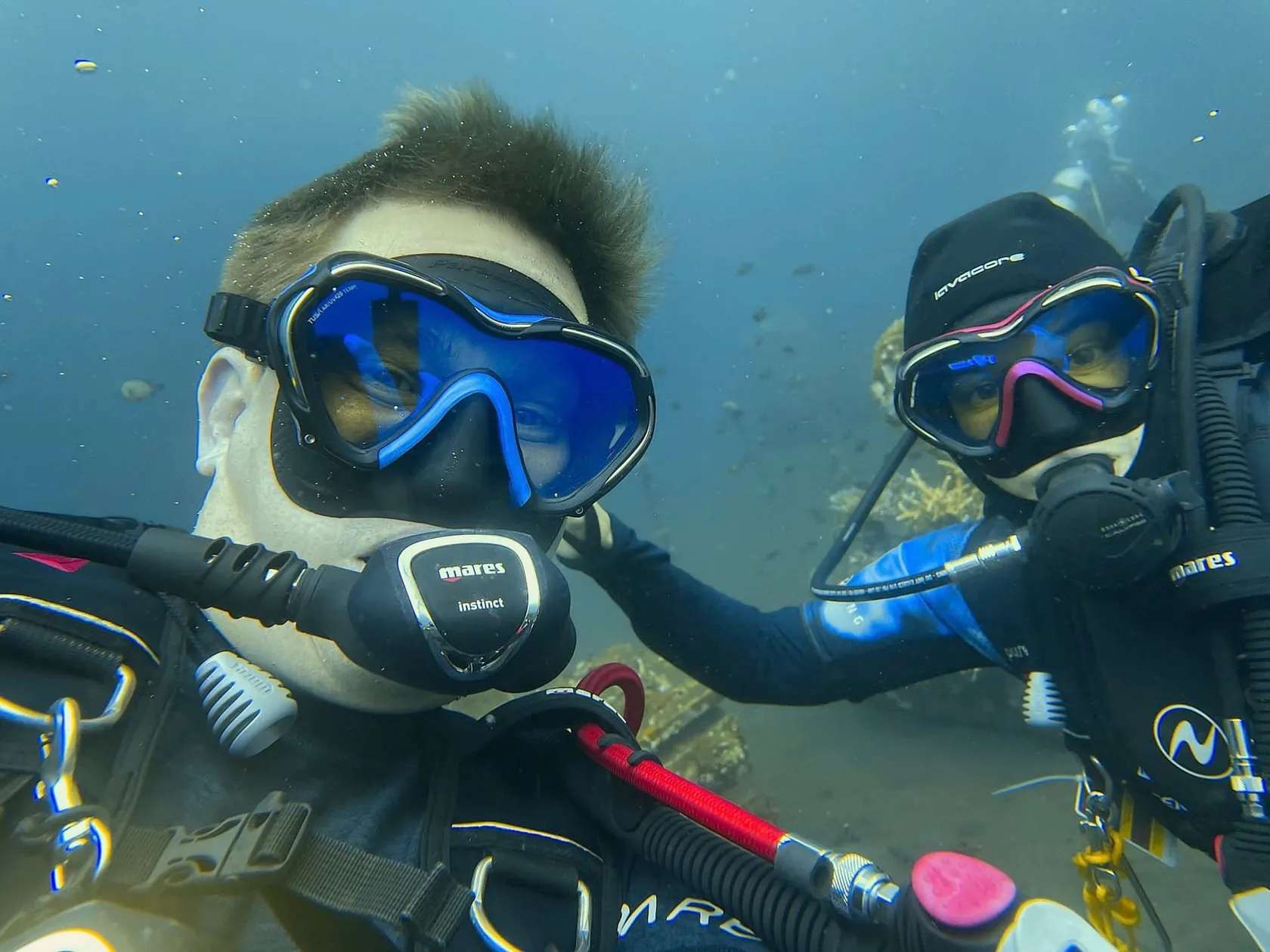 Caroline and Jonas underwater in full dive gear, looking into the camera