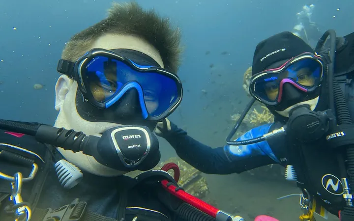Caroline and Jonas underwater in full dive gear, looking into the camera